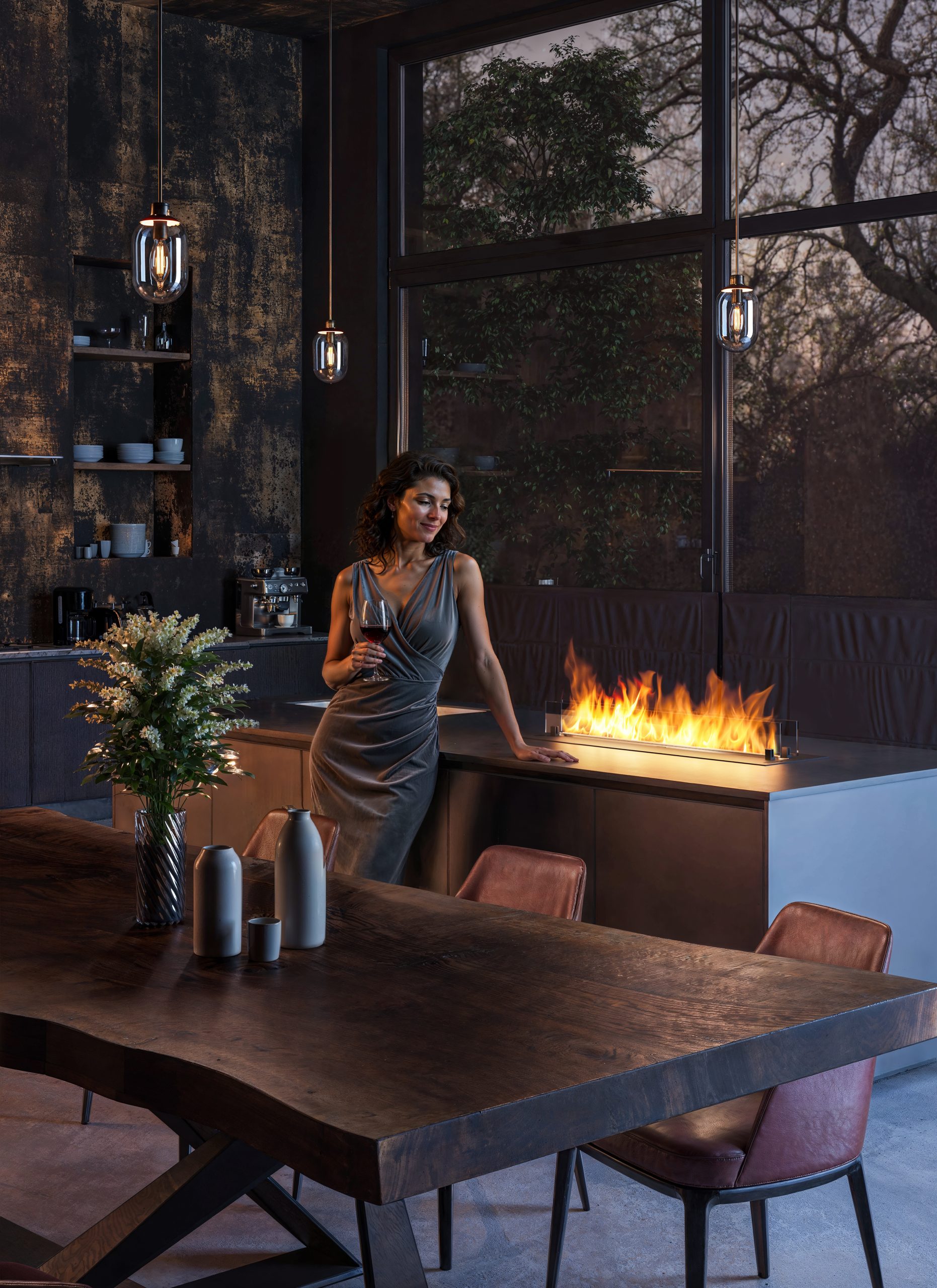 Una donna elegante in cucina di fianco ad un biocamino luxury verticale da pavimento accesso