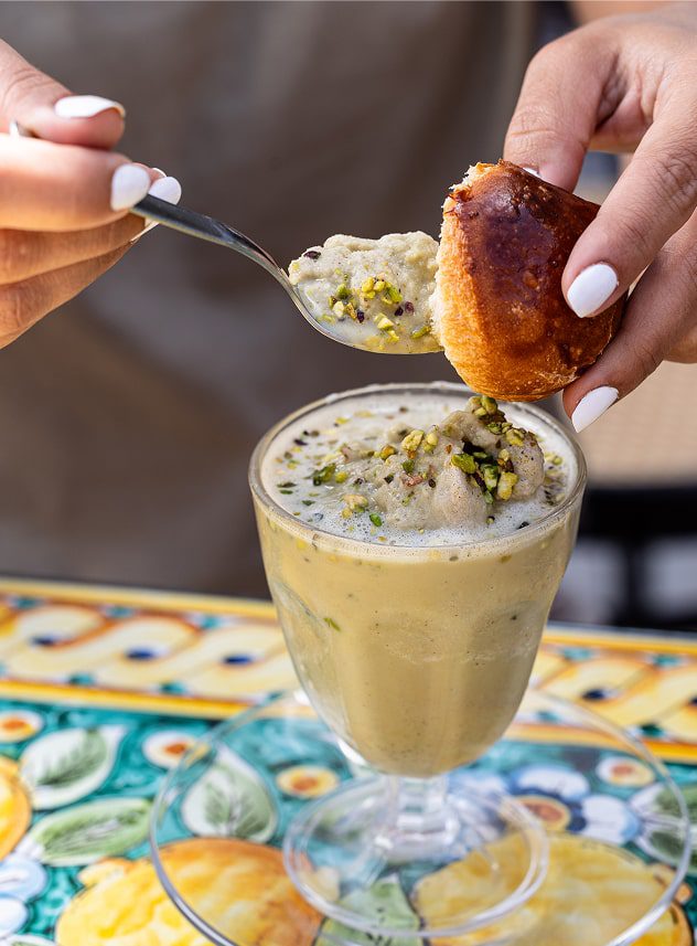 Close-up di una granita al pistacchio mangiata con il caratteristico "tuppo" della brioche siciliana