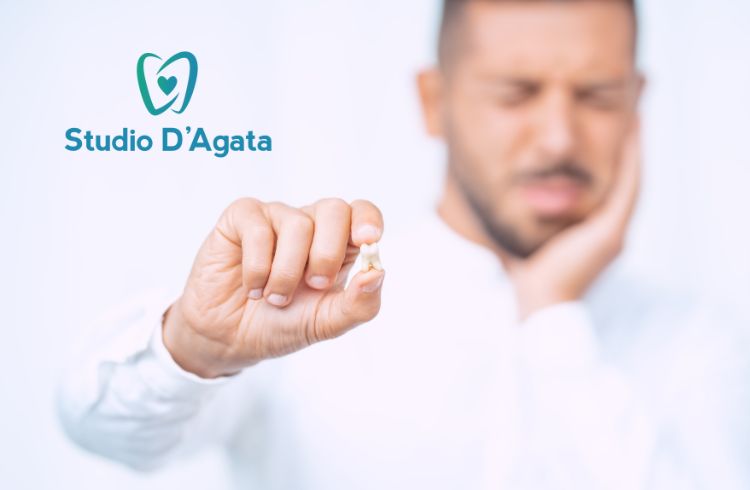 Uomo sullo sfondo si tocca la guancia a causa del dolore. In primo piano tiene un dente fra le dita